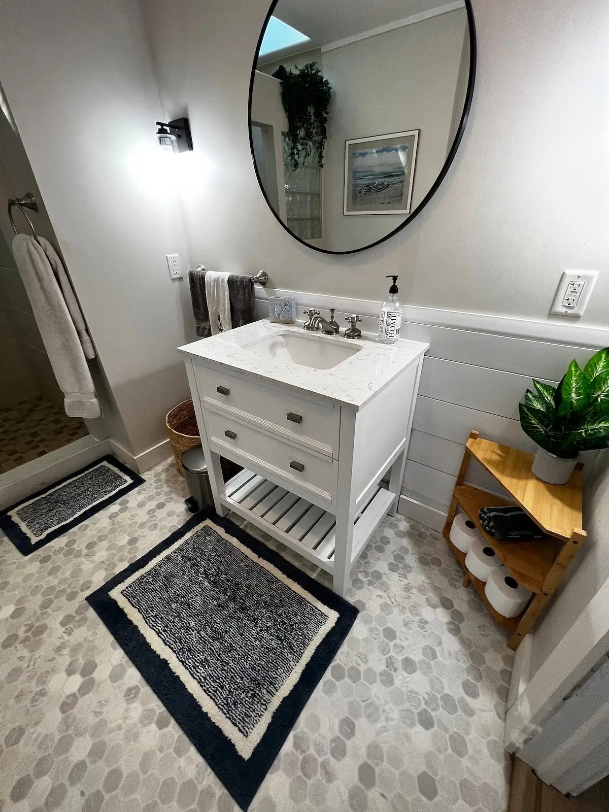 Bathroom with a white vanity, round mirror, and walk-in tiled shower