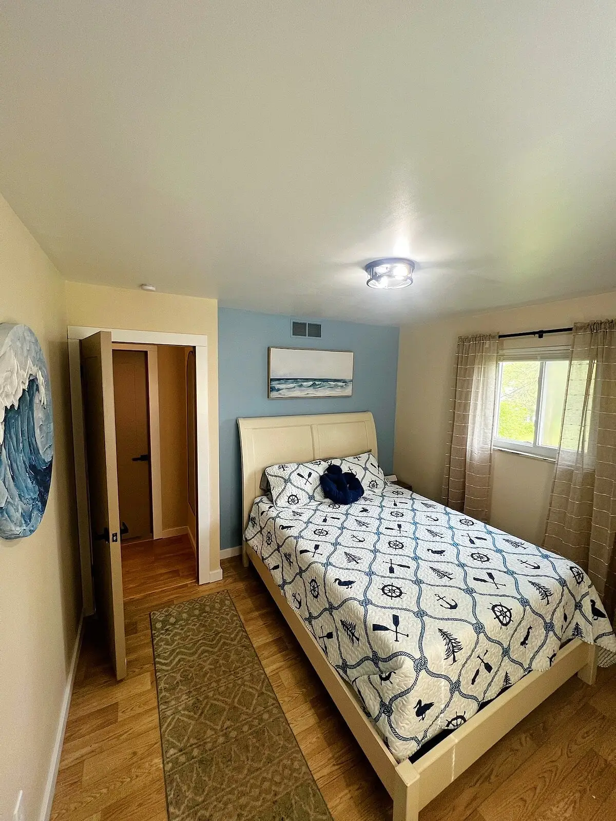 Queen bedroom with a nautical print quilt and two crossed oars mounted on the wall