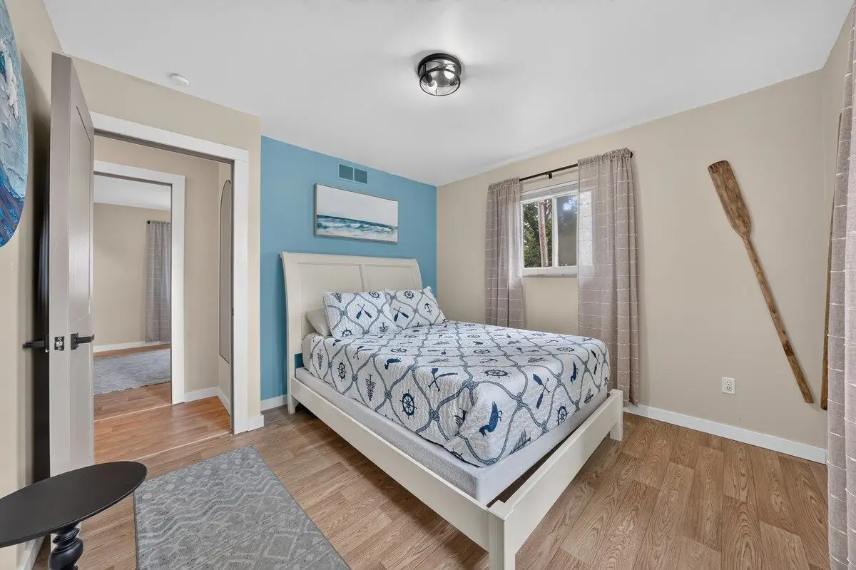Queen bedroom with a nautical quilt, a blue accent wall, and a wooden oar mounted beside the window