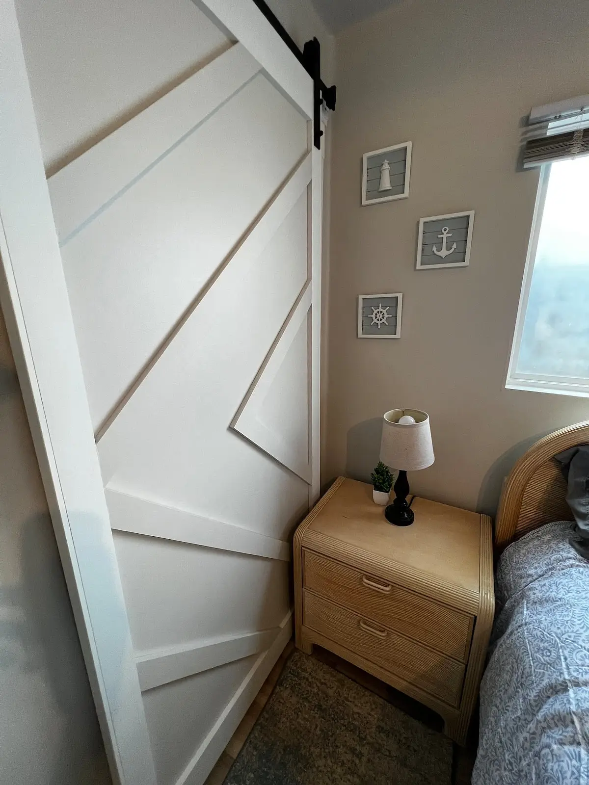 Bedroom with a queen bed, a sliding barn door, and framed nautical prints