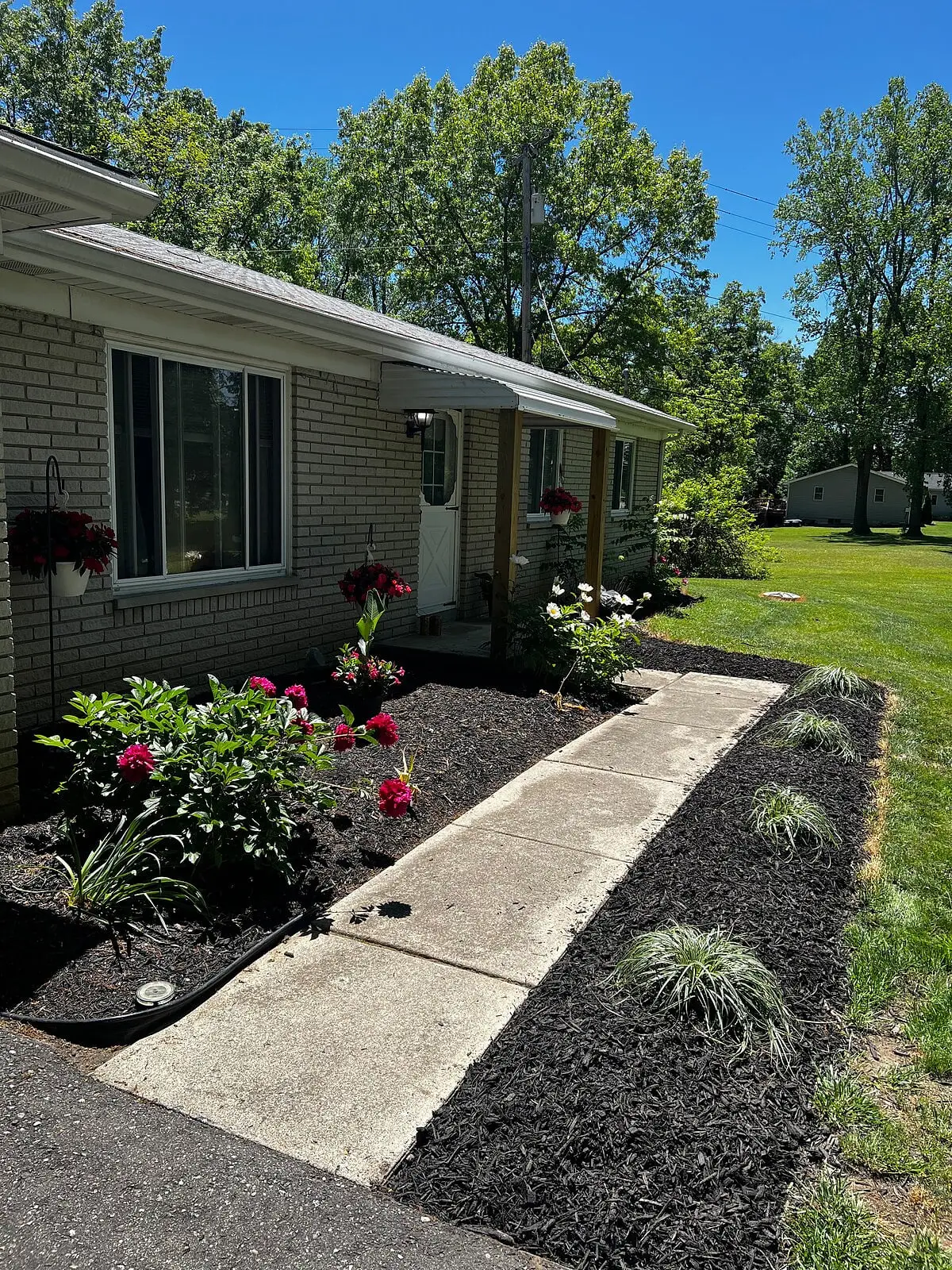 The front of the Paddle Inn, a single-storey brick ranch with flower beds along a concrete walk