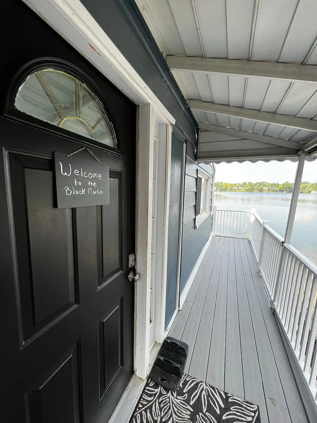 Covered front porch with a chalkboard sign reading Welcome to the Black Marlin, looking out to the lake