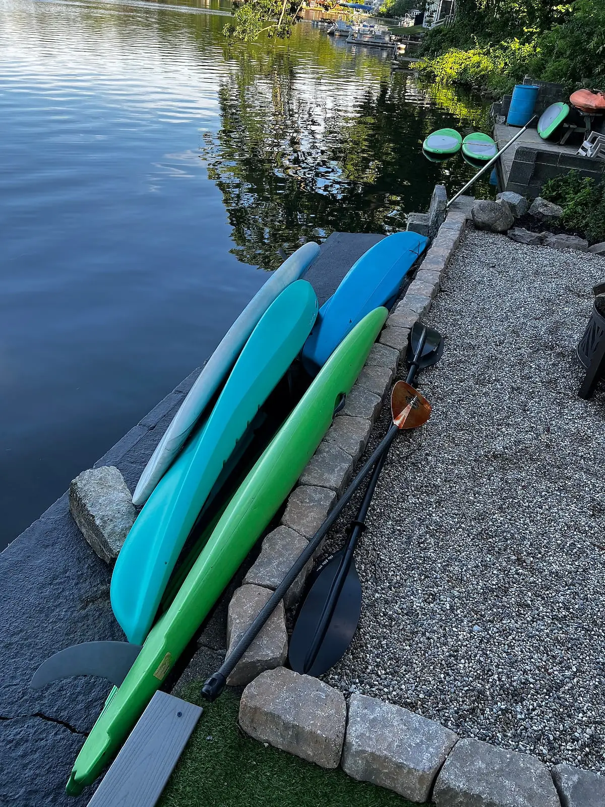 Kayaks and paddleboards lined up on the seawall at the water's edge